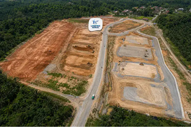 Aerial drone view of a Malaysian land development site showing earthworks at various stages with access roads and cleared land parcels
